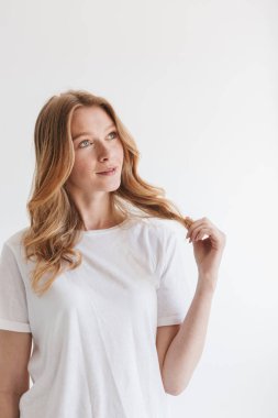 Beyaz duvar arka plan bir yana bakmaktan izole duran şaşırtıcı genç şirin kızıl saçlı kadın görüntüsünü.