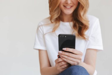 Cep telefonu kullaranarak beyaz duvar arka plan üzerinde izole genç Kızıl saçlı kadının kırpılmış görüntü.