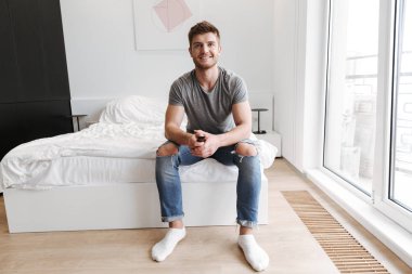 Onun yatak TV uzaktan oturan gülümseyen genç adam