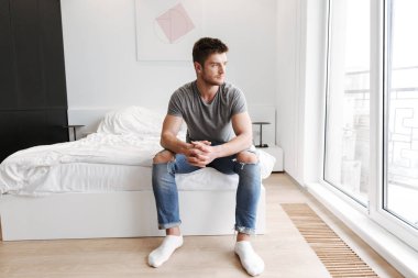 Onun yatağında evde oturan genç adam konsantre