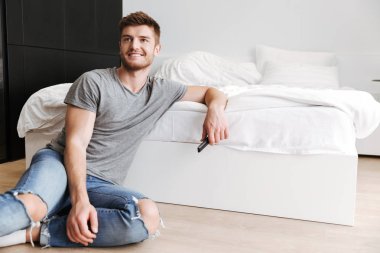 Onun yatak TV uzaktan oturan neşeli genç adam