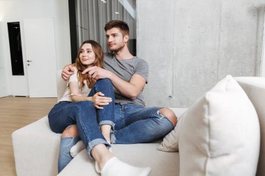 Mutlu genç çift birlikte evde bir kanepede oturan ve Tv izlerken sarılma
