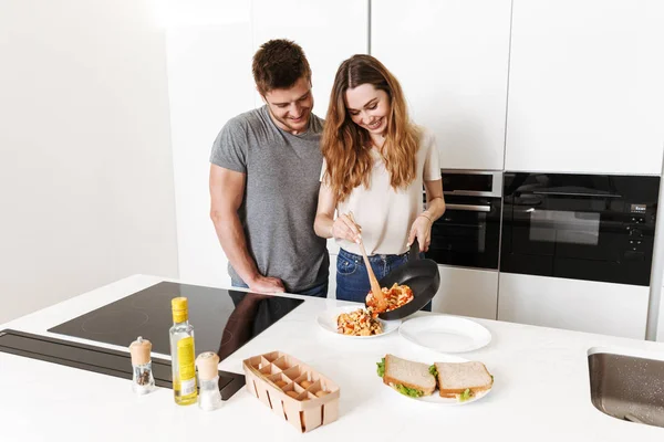 Smiling young couple cooking breakfast together in a kitchen