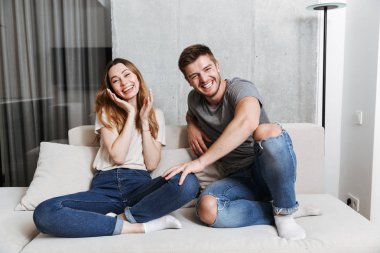 Mutlu çift birlikte evde bir kanepede otururken gülüyor