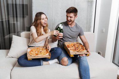 Evde pizza yeme ve birlikte otururken bira içme mutlu genç çift kanepe