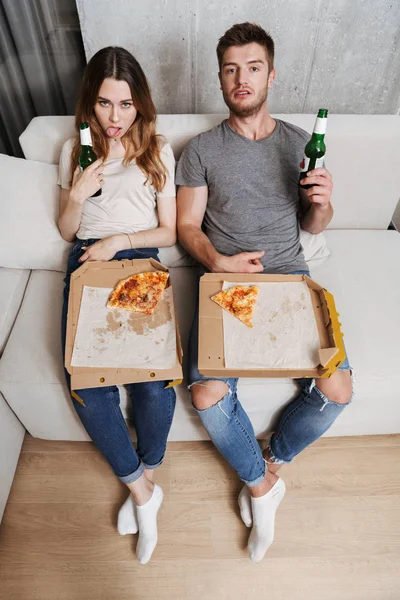 Mutsuz çift birlikte evde bir kanepede otururken pizza yemek