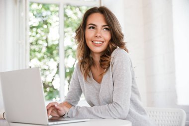 Görüntü sınıf bir kenara dizüstü bilgisayar kullanan seyir içinde oturan neşeli genç bayan.