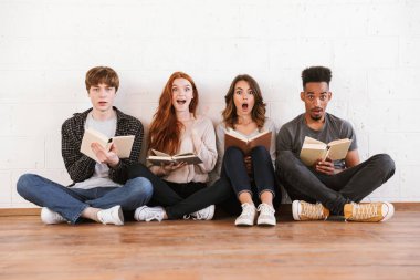 Görüntü kapalı kitap okuma kamera seyir beyaz duvar artalan üzerinde oturan şok duygusal genç arkadaşlar öğrenci.