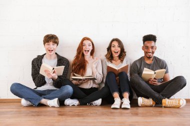 Görüntü kapalı kitap okuma kamera seyir beyaz duvar artalan üzerinde oturan sürpriz duygusal genç arkadaşlar öğrenci.