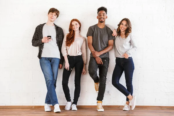 Image of smiling young friends students over white wall backgound indoors looking camera.