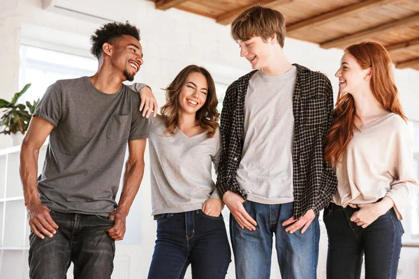 Görüntü genç neşeli arkadaşları öğrencilerin sınıfta kapalı birbirleri ile gülüyor konuşurken ayakta.