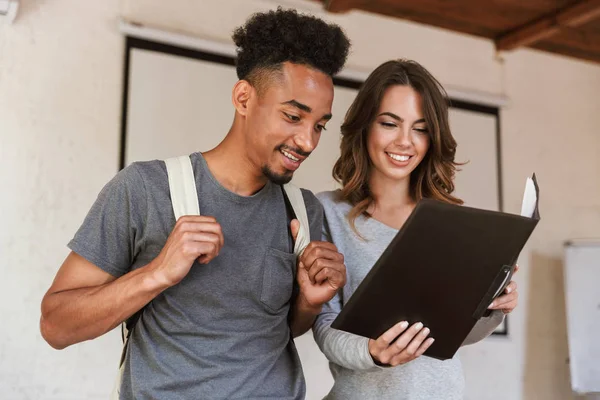 Mutlu arkadaş öğrenciler sınıfta klasörü okuma tutan görüntüsünü.