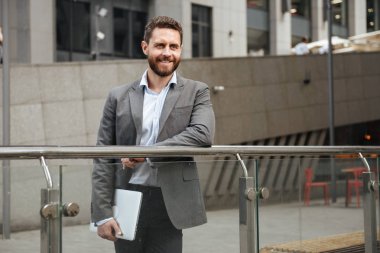 Görüntü başarılı girişimci insanın 40'lı formal giyim holding iş merkezi önünde dururken gümüş dizüstü el kapalı