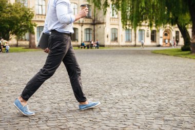 Formal giyim şehir sokak holding paket servisi olan restoran kahve ve gümüş laptop yürüyen genç ciddi adam kırpılmış görüntü