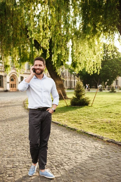 Parktan güneşli günde yürüyüş ve cep telefonu üzerinde konuşurken 30s uzunluk fotoğrafı memnun dostum rahat tam