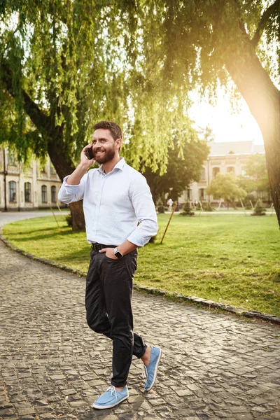 Şık gülümseyen, tam uzunlukta fotoğraf dostum parktan güneşli günde yürüyüş ve mobil telefon olan 30'lu