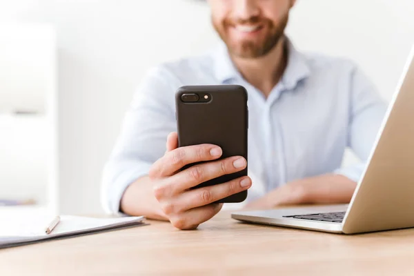 Beskuren Bild Glada Skäggig Man Sitter Office Arbetar Med Mobiltelefon — Stockfoto