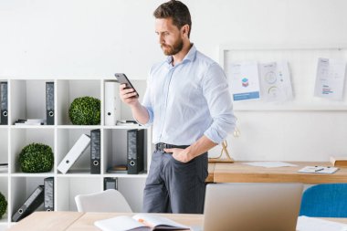 Konsantre görüntüsünü iş adamı kapalı cep telefonu kullanarak office çalışma sakallı. Bir kenara arıyorsunuz.