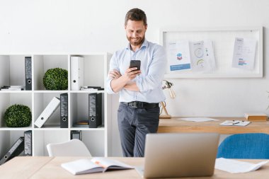 Mutlu görüntüsünü iş adamı kapalı cep telefonu kullanarak office çalışma sakallı. Bir kenara arıyorsunuz.