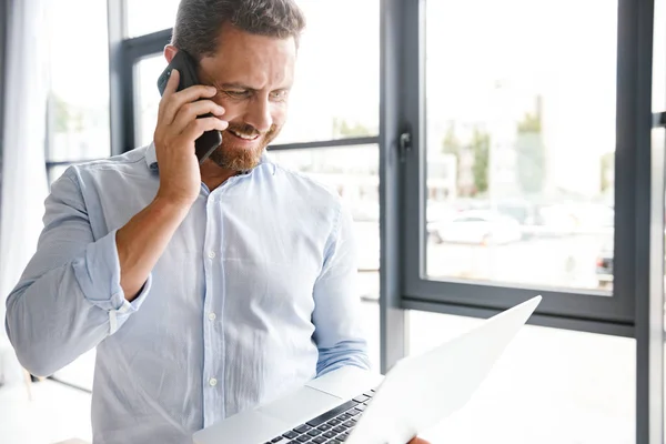 Hombre Negocios Sonriente Hablando Teléfono Móvil Analizando Ordenador Portátil Mientras — Foto de Stock