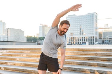 Açık havada duran süre gülümseyen sporcu germe yapmak egzersizleri