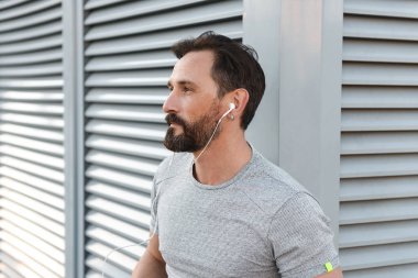 İmge-in yakışıklı güçlü olgun sporcu ayakta açık havada bir kenara dinleme müzik kulaklık arıyorum.