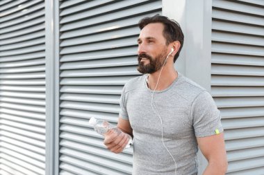 İmge-in yakışıklı güçlü olgun sporcu ayakta açık havada bir kenara dinleme müzik kulaklık arıyorum.