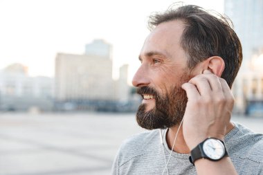 İmge-in yakışıklı güçlü olgun sporcu ayakta açık havada bir kenara dinleme müzik kulaklık arıyorum.
