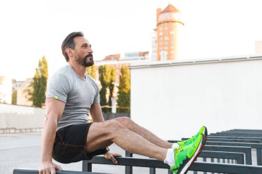 İmge-in yakışıklı konsantre güçlü olgun sporcu spor egzersizleri açık havada yapmak.