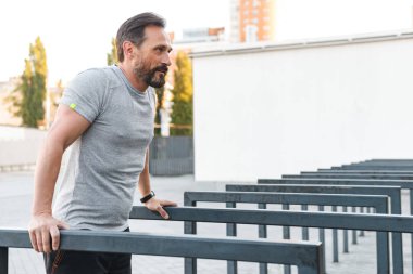 İmge-in yakışıklı konsantre güçlü olgun sporcu spor egzersizleri açık havada yapmak.