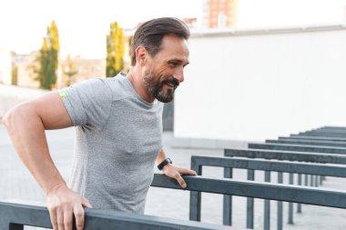 İmge-in yakışıklı konsantre güçlü olgun sporcu spor egzersizleri açık havada yapmak.