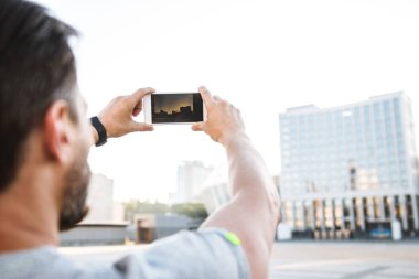 Arkadan görünüm fotoğraf street açık havada yürüyüş güçlü olgun sporcu cep telefonuyla fotoğraf olun.