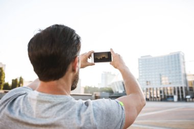 Arkadan görünüm fotoğraf street açık havada yürüyüş güçlü olgun sporcu cep telefonuyla fotoğraf olun.