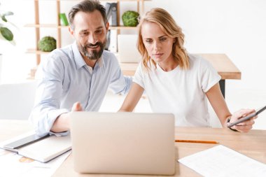 Birlikte laptop ile ofiste otururken bir proje üzerinde çalışıyor emin iş arkadaşları birkaç