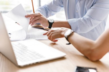 Birlikte laptop ve evrak ile ofiste otururken bir projede çalışan meslektaşlarının genç çiftin yakın çekim