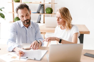 Birlikte laptop ile ofiste otururken bir proje üzerinde çalışıyor konsantre meslektaşlarının çift