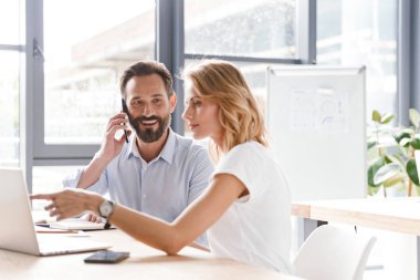 Dost meslektaşlarının çalışmaları sırasında ofiste oturan ve dizüstü bilgisayarda çalışıyor tartışan çift