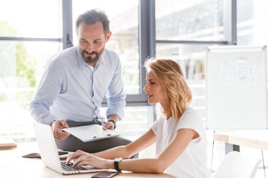 Ofiste oturup dizüstü bilgisayarla çalışırken iş tartışan birkaç meslektaşım var.