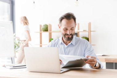 Dost adam Yöneticisi bir arka plan ile işbirliği işçisi kadın ofiste otururken dizüstü bilgisayar belgelerle çalışma