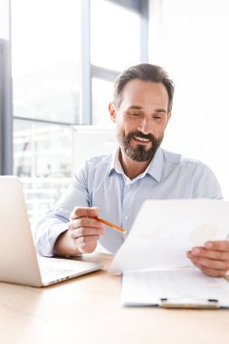 Bir arka plan ile işbirliği işçisi kadın ofiste otururken dizüstü bilgisayar ve belgeler üzerinde çalışan başarılı adam Yöneticisi