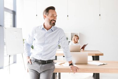 Gülümseyen adam Yöneticisi ile bir arka plan üzerinde işbirliği işçisi kadın ofis dururken bir masa üzerine eğilerek