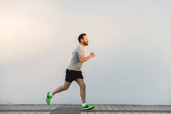 Sonriente Deportista Corriendo Aire Libre Sobre Fondo Pared Ciudad — Foto de Stock