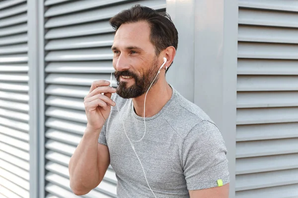 İmge-in yakışıklı güçlü olgun sporcu ayakta açık havada bir kenara dinleme müzik kulaklık arıyorum.