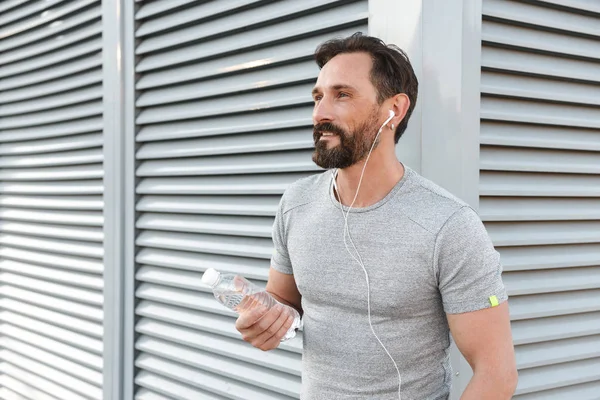 İmge-in yakışıklı güçlü olgun sporcu ayakta açık havada bir kenara dinleme müzik kulaklık arıyorum.