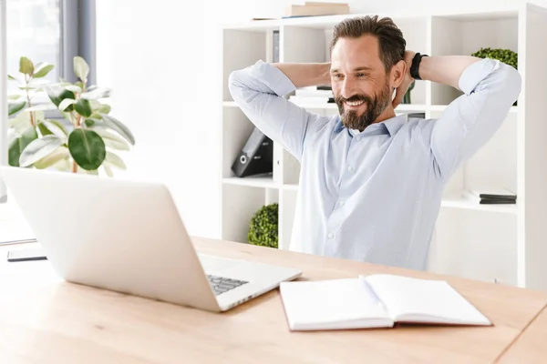 Hombre Negocios Sonriente Mirando Ordenador Portátil Mientras Relaja Escritorio Oficina —  Fotos de Stock