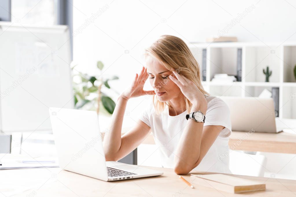 Exhausted businesswoman working on laptop computer while sitting at the office desk