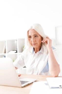 Kapalı dizüstü bilgisayar ile çalışma ofisinde oturan konsantre Olgun kadın görüntüsünü.