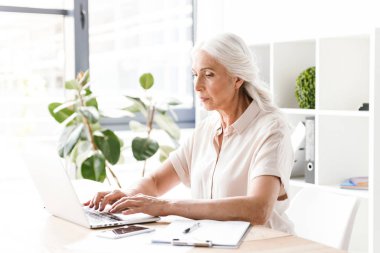 Kapalı dizüstü bilgisayar ile çalışma ofisinde oturan Olgun kadın fotoğrafı.