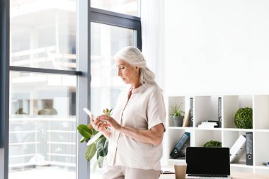 Ofiste duran cep telefonu tutan emin olgun busienss kadın