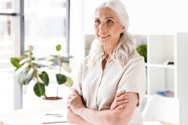 Ofiste katlanmış ve uzak seyir silah ile duran emin olgun busienss kadın